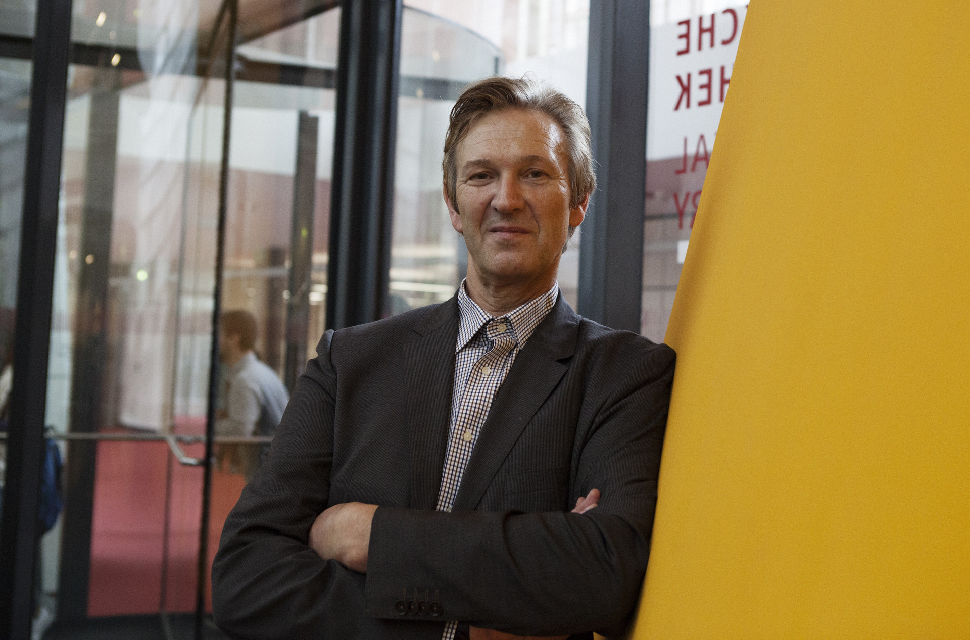 Mann in Anzug & Krawatte im Eingangsbereich eines Gebäudes